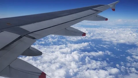Wing of an airplane flying above the clouds with blue sky Stock Footage 71100562