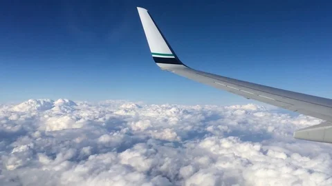 Wing of an airplane flying above the clouds. People look at the sky from the Stock Footage