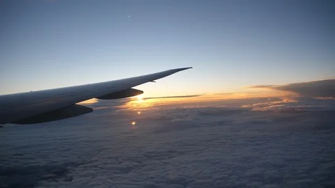 Wing of an airplane flying above the clouds with sunset sky Stock Footage 106605901