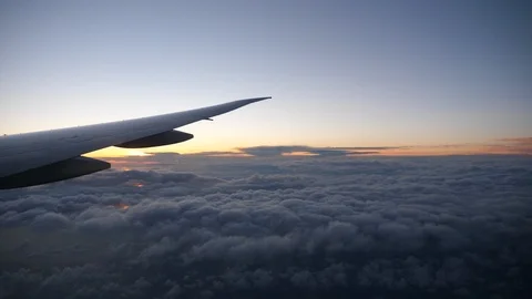 Wing of an airplane flying above the clouds with sunset sky Stock Footage 106607148