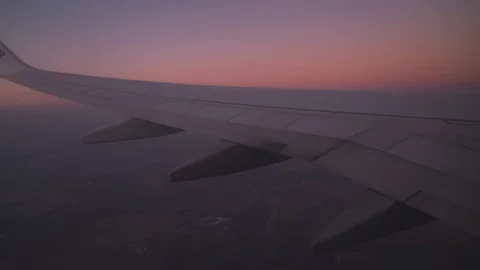 Wing of an airplane flying above the clouds at sunrise Stock-Footage 121618243