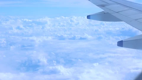 Wing of an airplane flying above the clouds on blue sky Stock Footage 248497372