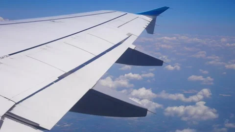 Wing of an airplane flying above the clouds on blue sky. View from a window of Video stock 252470501