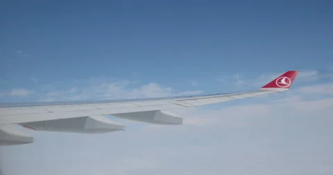 Wing of an airplane flying above the clouds, view from the window. Travelling on Stock Footage 275534407