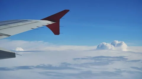 Wing of an airplane flying above a layer of clouds during a beautiful sunny day Stock Footage 310827818