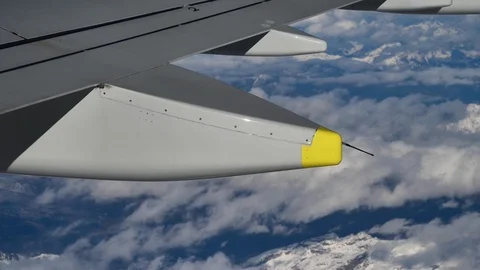 Wing of airplane flying over clouds and snowy mountains Alps Stock Footage 119486553