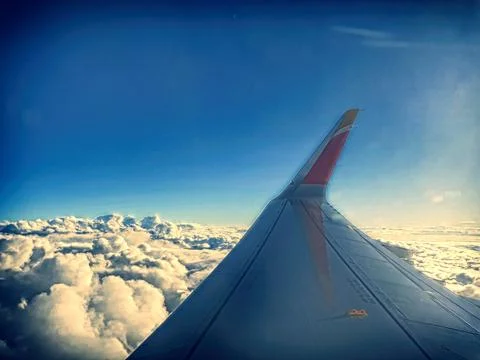 Wing of an airplane flying over the clouds Stock Photos