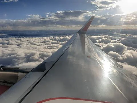 Wing of an airplane flying over the clouds Stock Photos