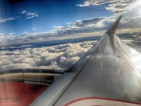 Wing of an airplane flying over the clouds Stock Photos