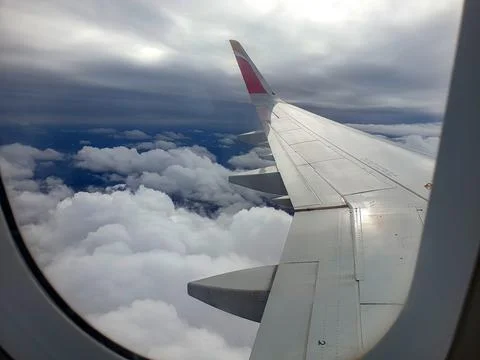 Wing of an airplane flying over the clouds Stock Photos