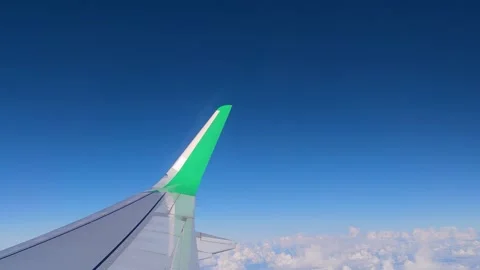 The Wing of an Airplane Flying Over Fluffy White Clouds With a Clear Sky.  Stock Footage 227339935