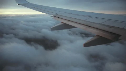 The wing of an airplane looking through the passenger window above the clouds 4K Stock Footage 130282549
