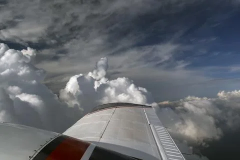Wing of light-engine aircraft against the background of cumulus clouds in f.. Stock Photos