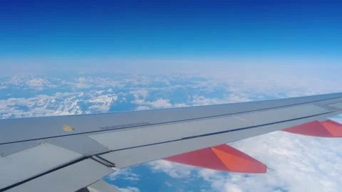 Wing plane air thick clouds below snow capped mountains across window to Vídeo Stock 320845614