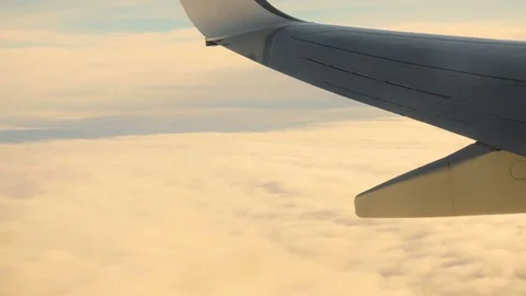 Wing of a Plane, Clouds and Sky at Sunset Seen Through a Window While Flying Stock Footage 72118855
