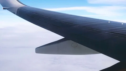 Wing of a Plane, Clouds and Sky Seen Through a Window While Flying Stock Footage 72119131