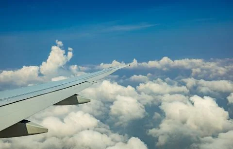 Wing of plane over white clouds. Airplane flying on blue sky. Scenic view fro Foto stock