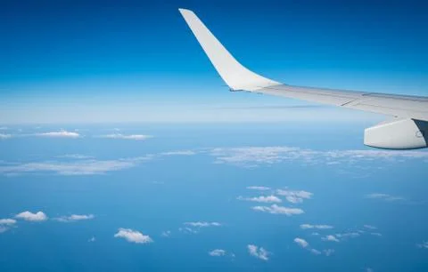 Wing of plane over white clouds. Airplane flying on blue sky. Scenic view fro Stock-Fotos