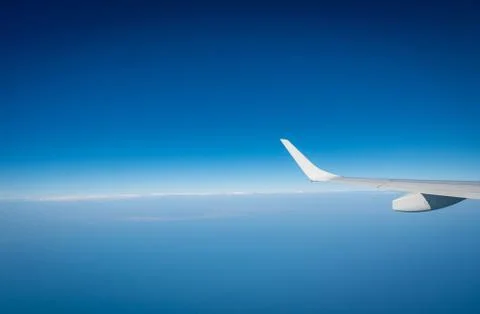 Wing of plane over white clouds. Airplane flying on blue sky. Scenic view fro 库存照片