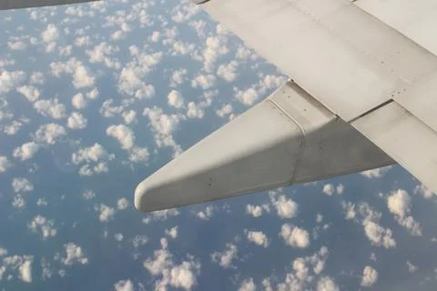 Wing of the plane on sky background - plane wing with cloud patterns Stock Photos