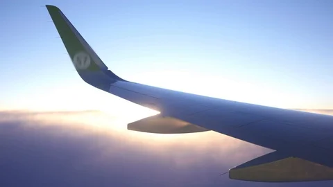 The wing of the plane from the window is high in the sky above the clouds at Stock Footage 86100116