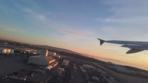 Wing side view of plane taking off from LAX at sunset Stock Footage