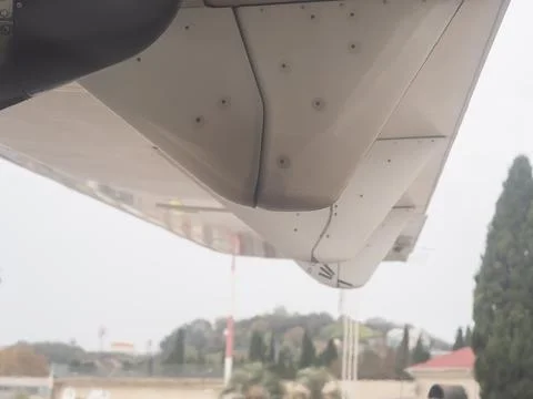 The wing of a small plane standing on the runway. View from the porthole Stock Photos