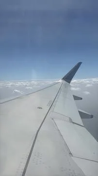 Wing view above a sea of clouds, clean aviation geometry, hybrid work era t.. Stock Photos