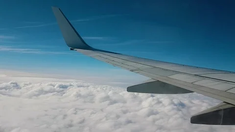 Wing view of a plane flying over the clouds Stock Footage 82393795