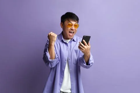 Winner Man Rejoicing Smartphone. Extremely Happy Asian Guy Raised Arm Gesturing Foto stock