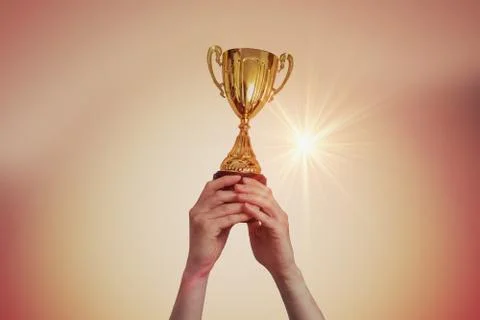 Winner is raised up a trophy in sunset. Stock Photos