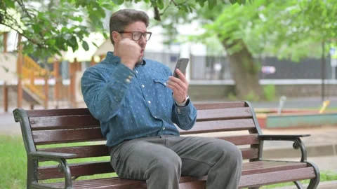 Winning Middle Aged Man Expressing Excitement While Using Phone Outdoor 動画素材 311360056