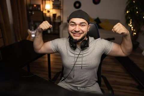 Winning round in a computer video game. A bearded man with a headset enjoys the Stock Photos