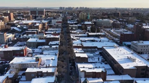 Winter aerial drone flight over snow covered city rooftops at sunset. Stock Footage 344245393
