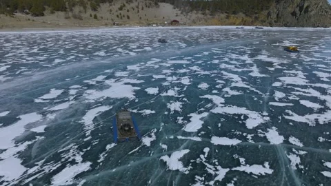 Winter aerial view of ice patterns and vehicles in Peschanaya Bay, Baikal Stock Footage 336294940