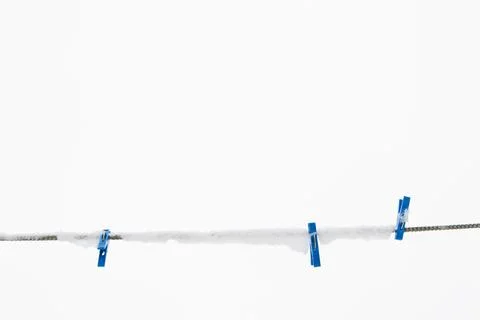 Winter background: clothesline covered with snow, several blue clothespins, s Foto stock