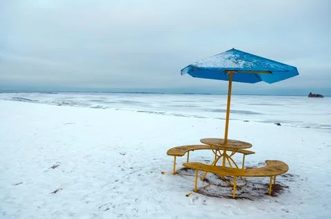 Winter beach with empty table and umbrella Stock Photos
