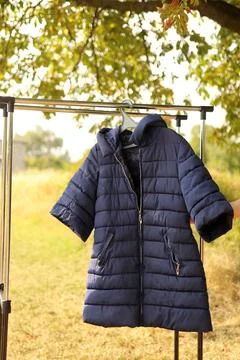 A winter blue down jacket hangs on a hanger. Stock Photos
