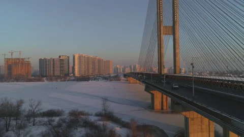 Winter cityscape with construction site and bridge over frozen river at dusk Stock Footage 159381385