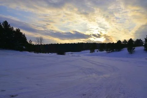 Winter cloudy sunset in a snowy forest in the Urals Stock Photos