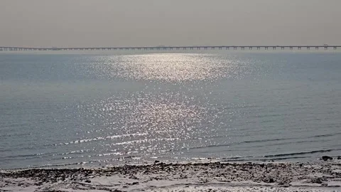 Winter Coastal Landscape with Sunlight Reflection and Distant Sea Bridge, 4K Vídeos de archivo 330165321