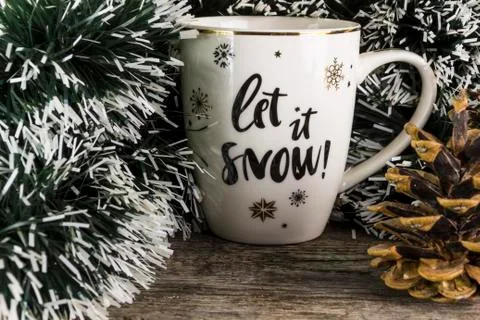Winter cup "Let it Snow" on the background of a tree, a tree and a pine cone Foto stock
