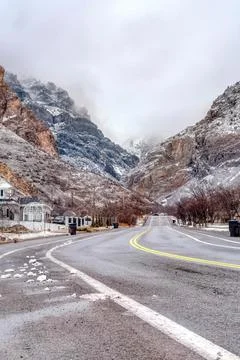 Winter day on scenic town with highway road and rocky mountain dusted with snow Foto stock