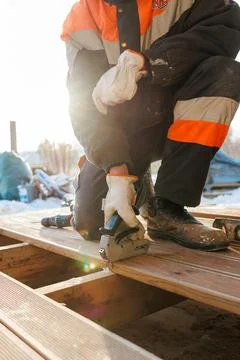 Winter deck installation as worker fastens board with stapler Stock-Fotos