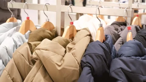 Winter down jackets hanging on wooden hangers in clothing store. Stock Footage 289262074