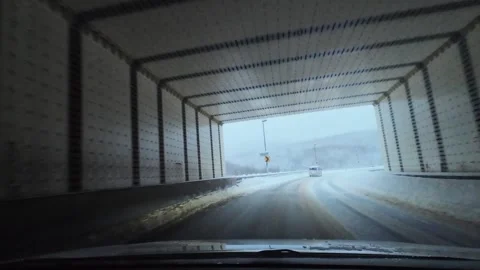 Winter driving inside tunnel exiting to snowy mountain curve Video stock 333091552