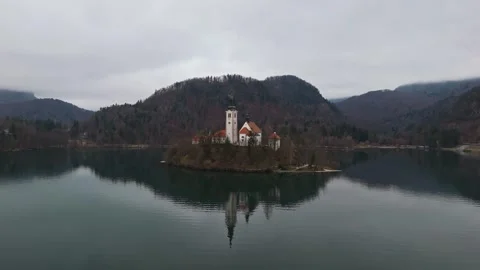 A winter drone view of Lake Bled's island church amid calm water and mountains Stock Footage 336467790