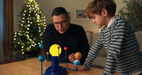 Winter evening. Dad and son are studying the planets. A man with glasses in Stockbeeldmateriaal 210486444