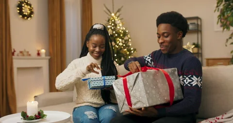 Winter evening, shimmering Christmas tree. Two young people of African 스톡 동영상 211563264