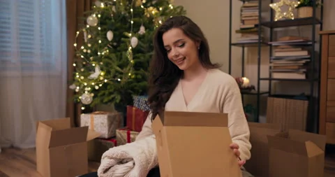 Winter evening. Smiling brunette prepares gifts for friends. Boxes lie on the 库存影片 211398451
